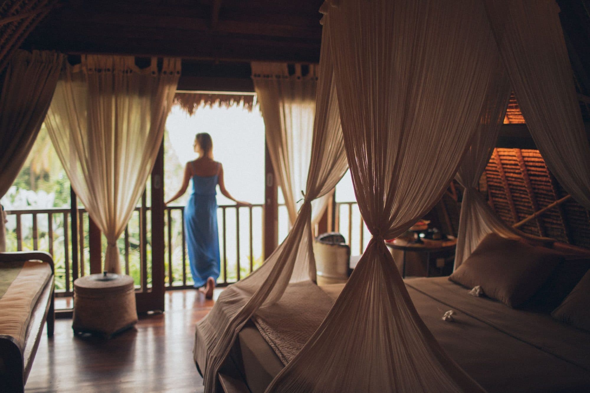 A guest standing between canopy curtains in a villa bedroom