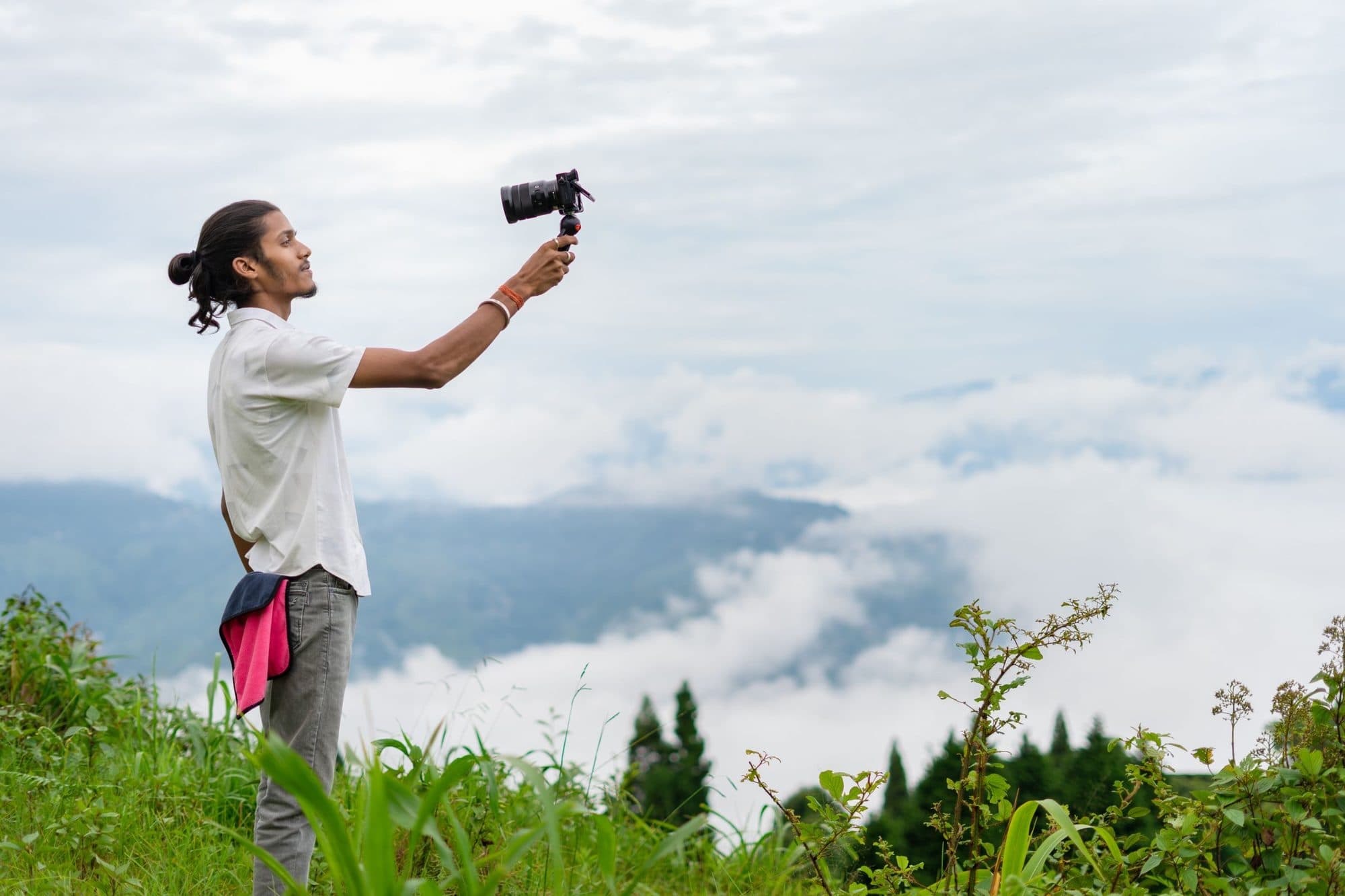 A creator filming a misty mountain landscape on a phone