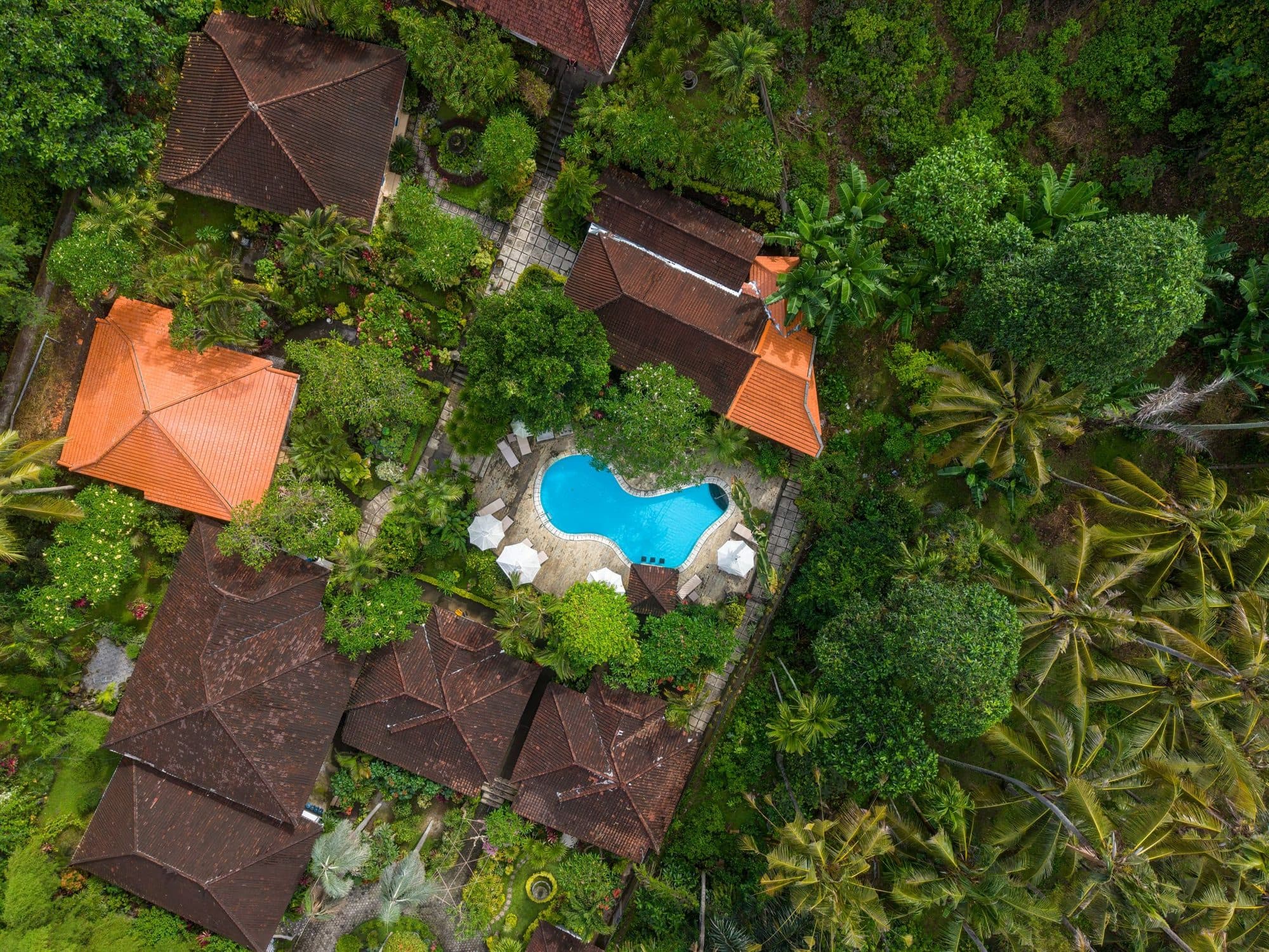 Aerial view of a tropical villa with a pool surrounded by greenery, a strong hero image for a hotel website