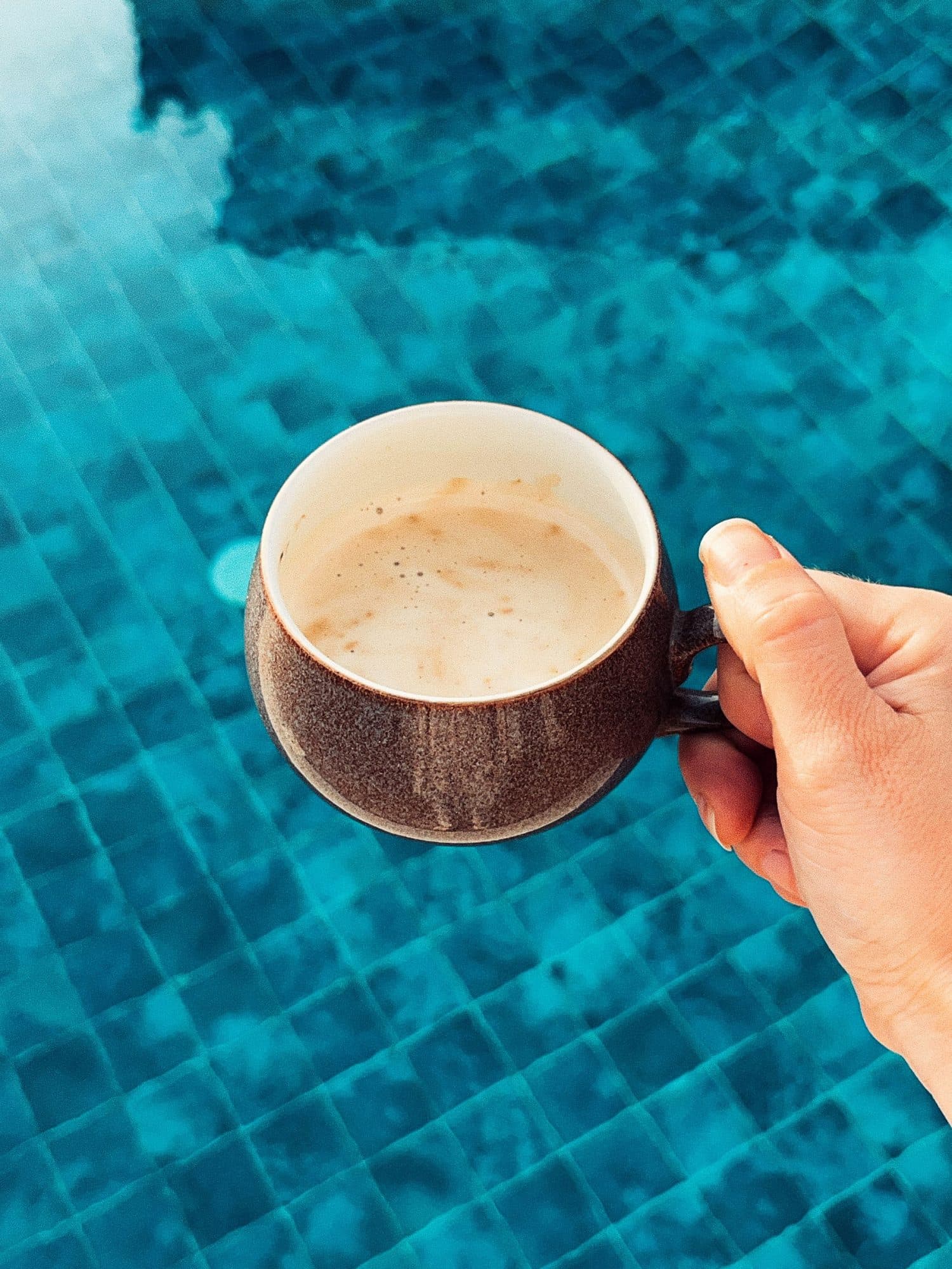 Holding a coffee above the water's edge
