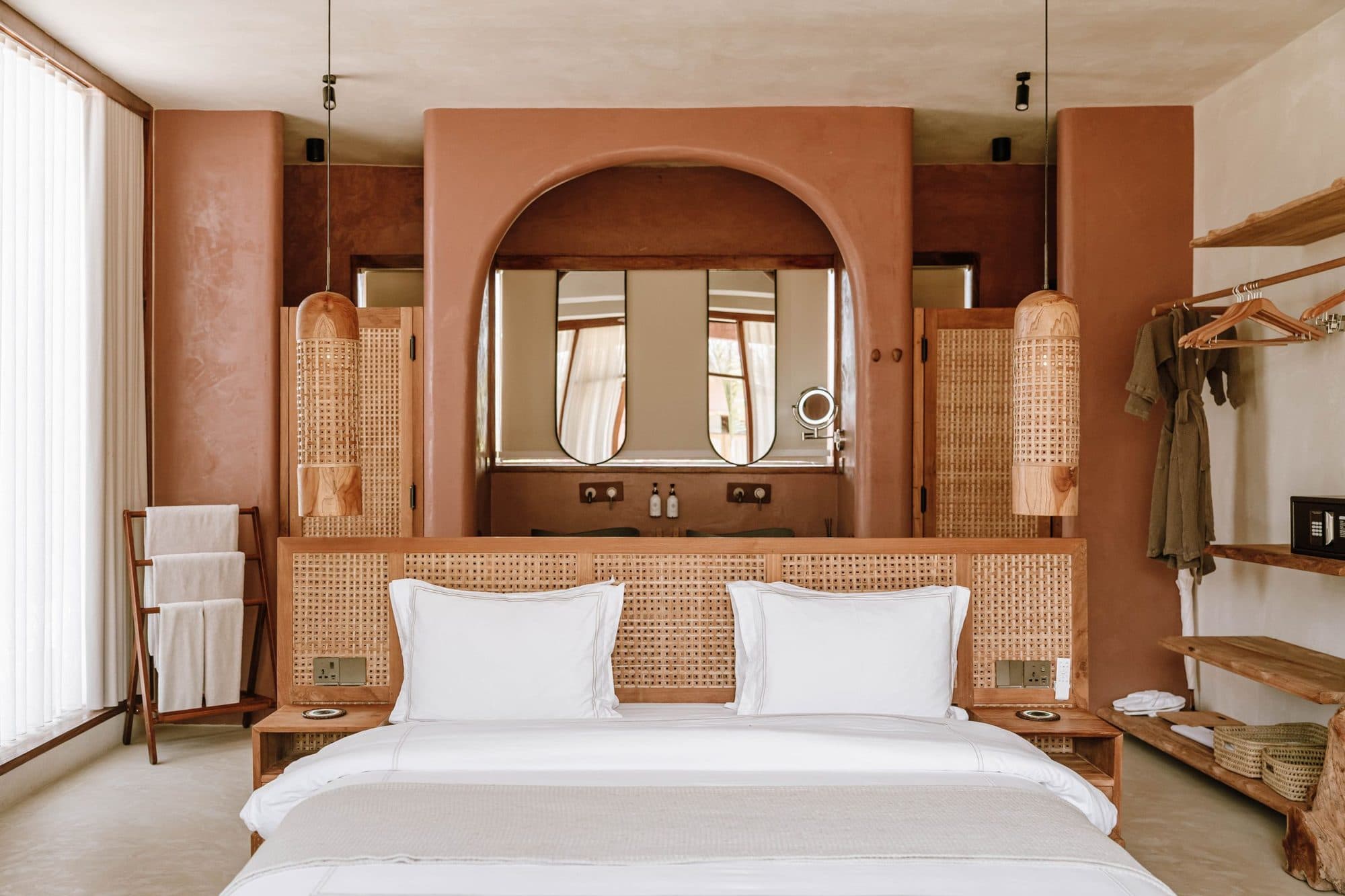 A boutique hotel room with rattan headboard and terracotta walls