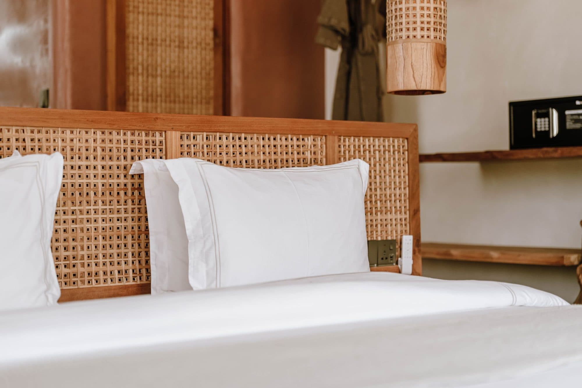 White bed with rattan headboard in warm afternoon light
