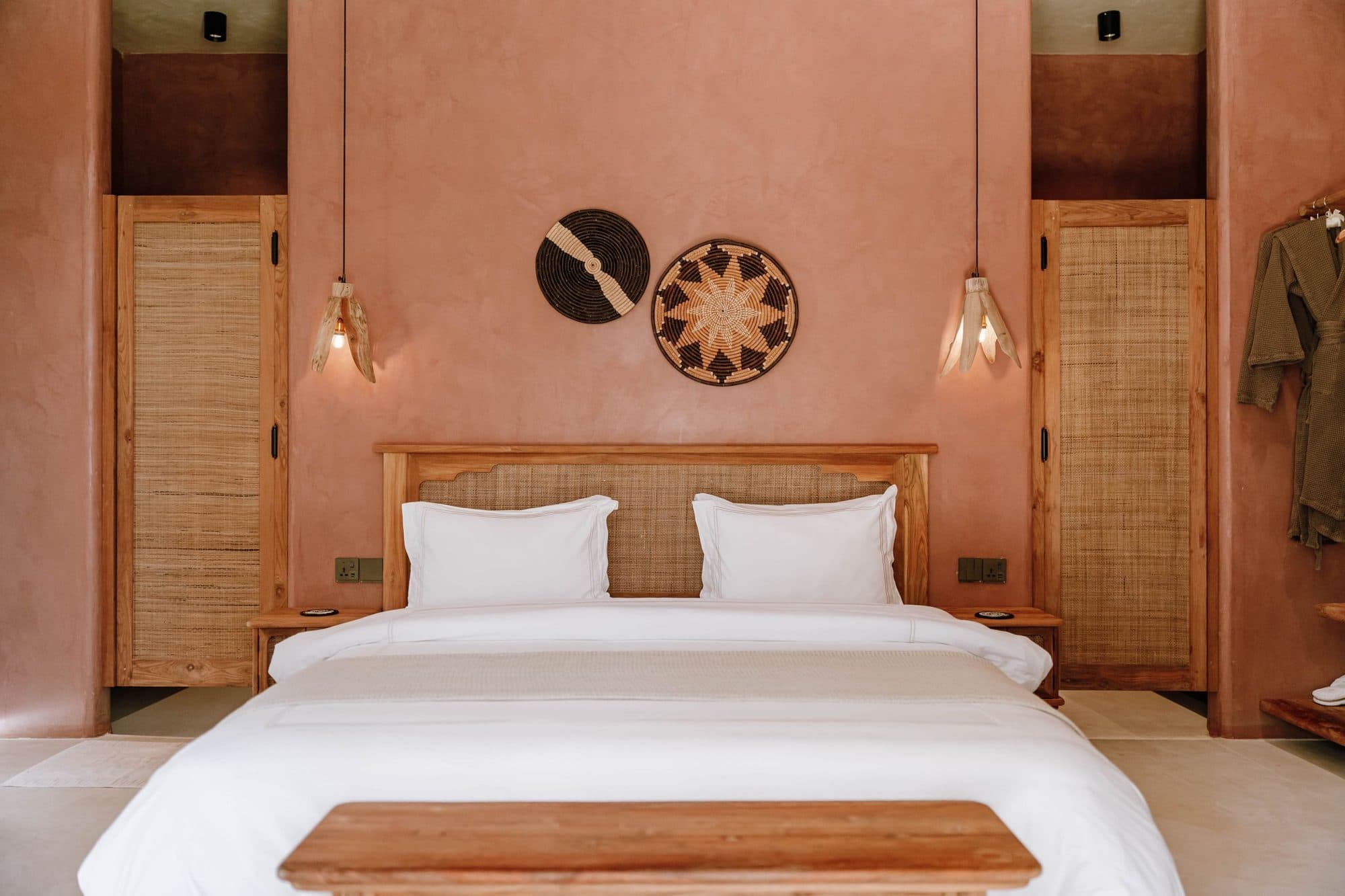 Boutique hotel room with terracotta walls, rattan panels and a crisp white bed