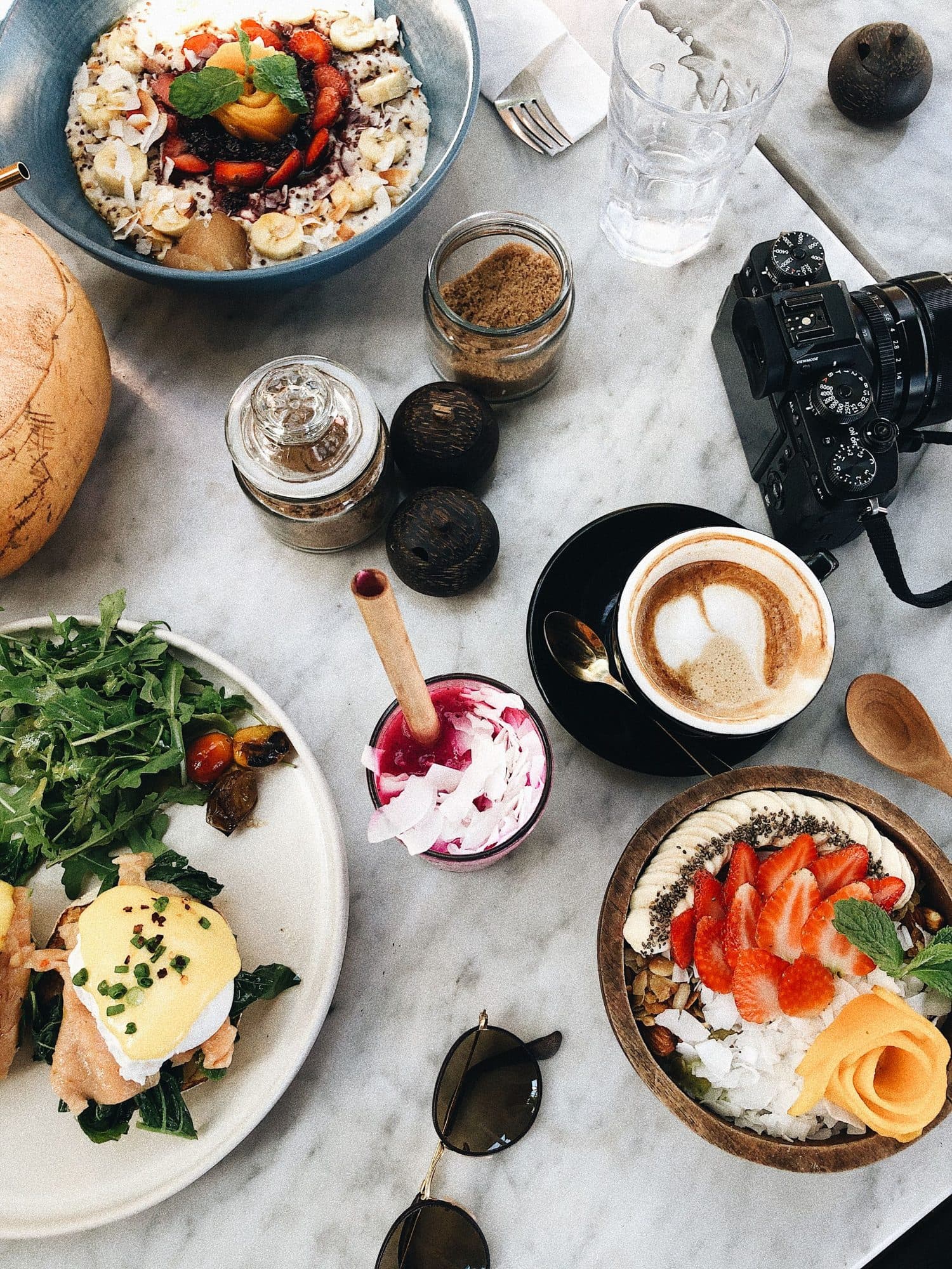 A marble table with brunch dishes, drinks and a camera