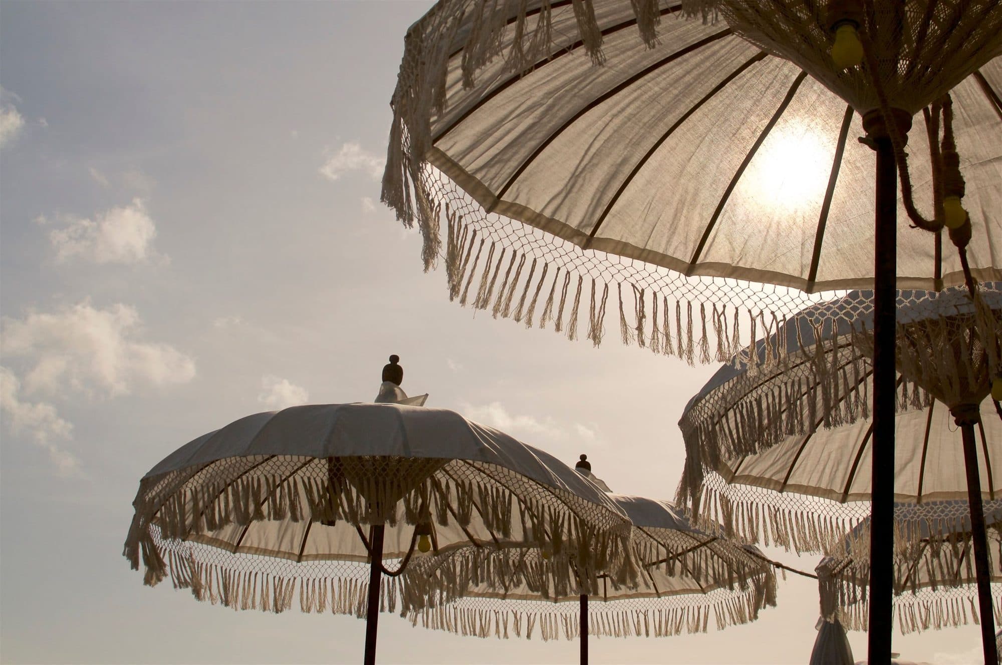Fringed umbrellas against a hazy sunset on the beach