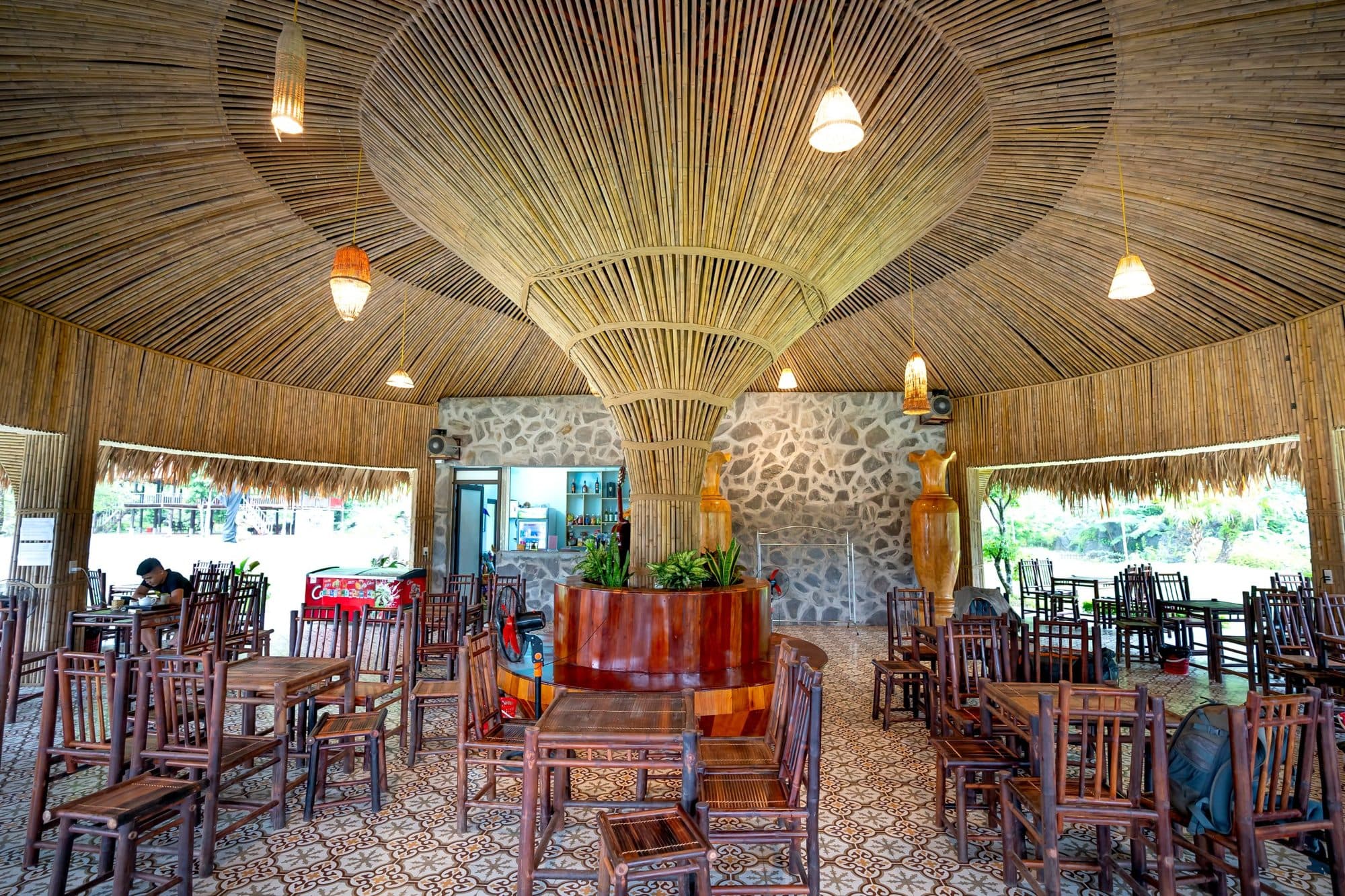 A bamboo-roofed restaurant dining room set for service