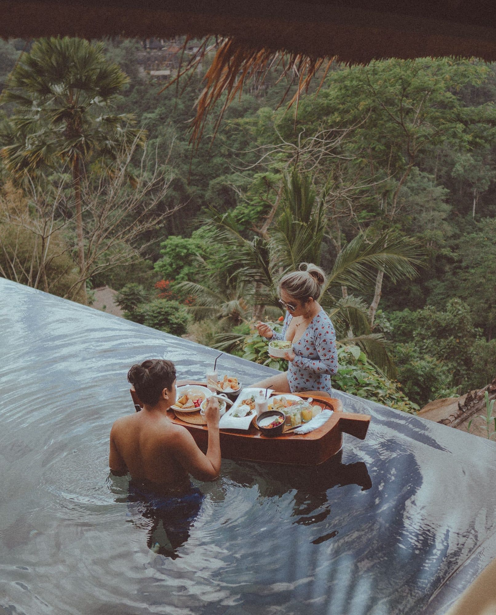 A couple sharing breakfast on a floating tray in a villa infinity pool