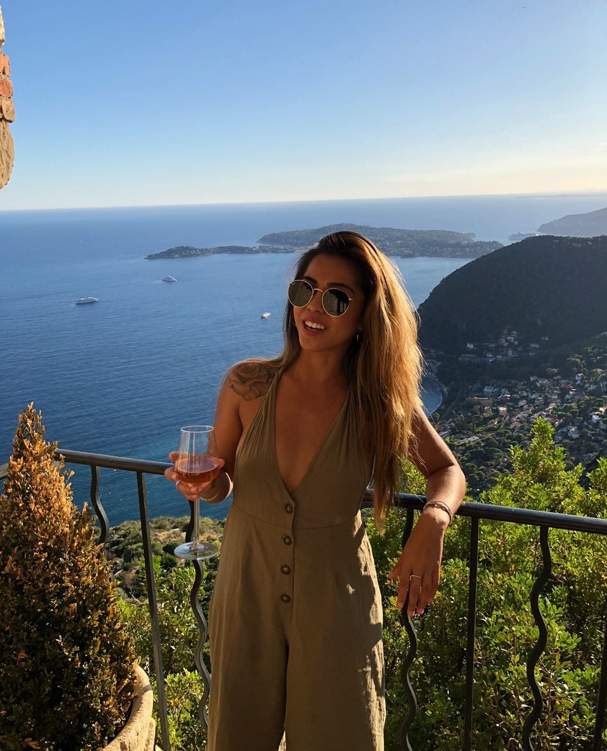 Tamara with a glass of rosé on a clifftop terrace above the sea