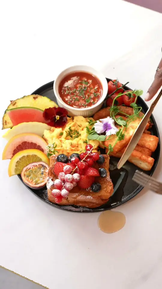 A tropical breakfast plate with fruit and sambal being served
